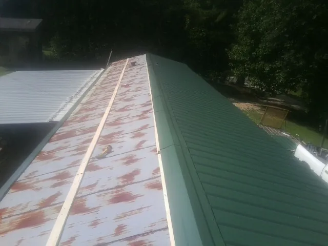 Old rusted panels beside newly installed green metal roofing — Wind Damage Roof Repair by Roofing Brothers in Middlefield