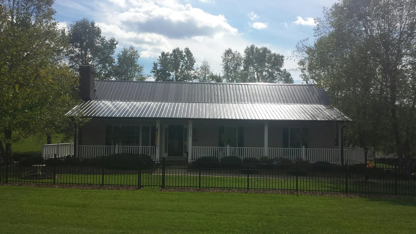Gray metal roof on a brick ranch with a full width front porch — Gutter Guard Installation work by our crew in Middlefield